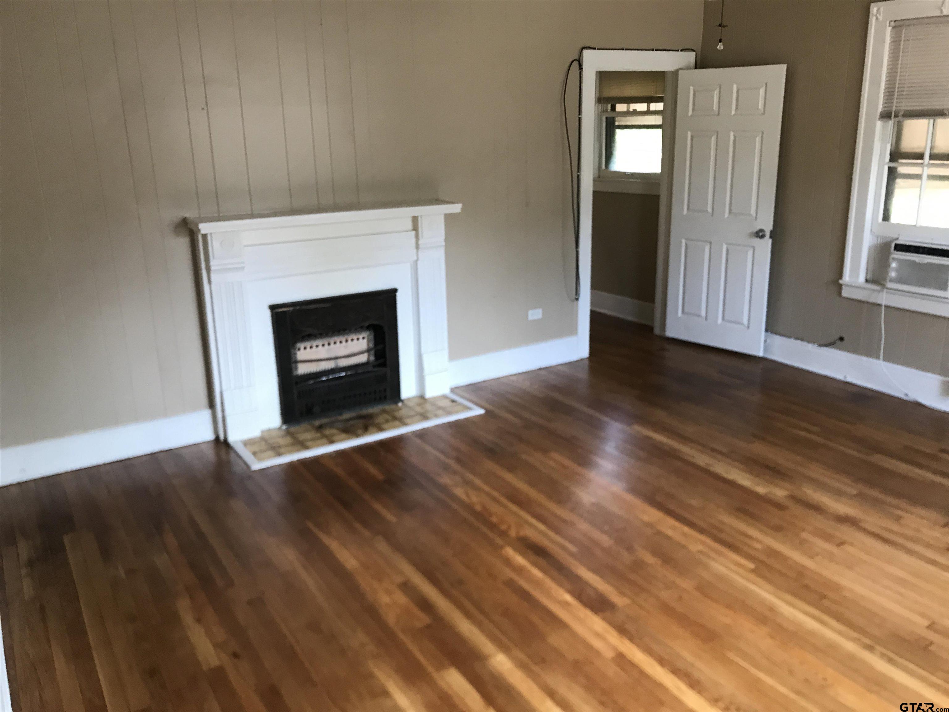 208 West Phillips Street, Unit 200 Tyler, TX 75701 - Photo 3 of 11 an empty room with wooden floor fireplace and windows