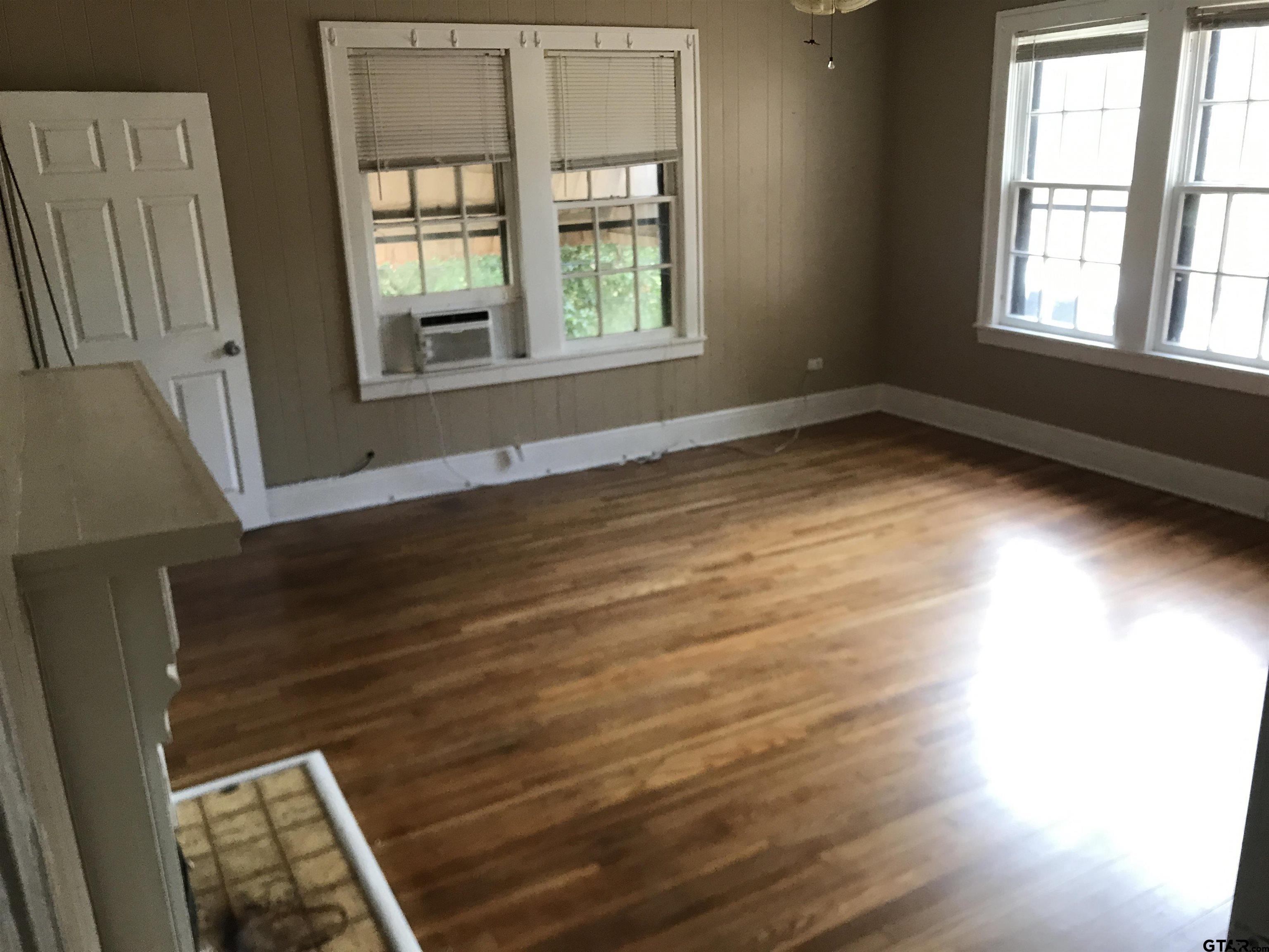 208 West Phillips Street, Unit 200 Tyler, TX 75701 - Photo 4 of 11 an empty room with wooden floor and windows