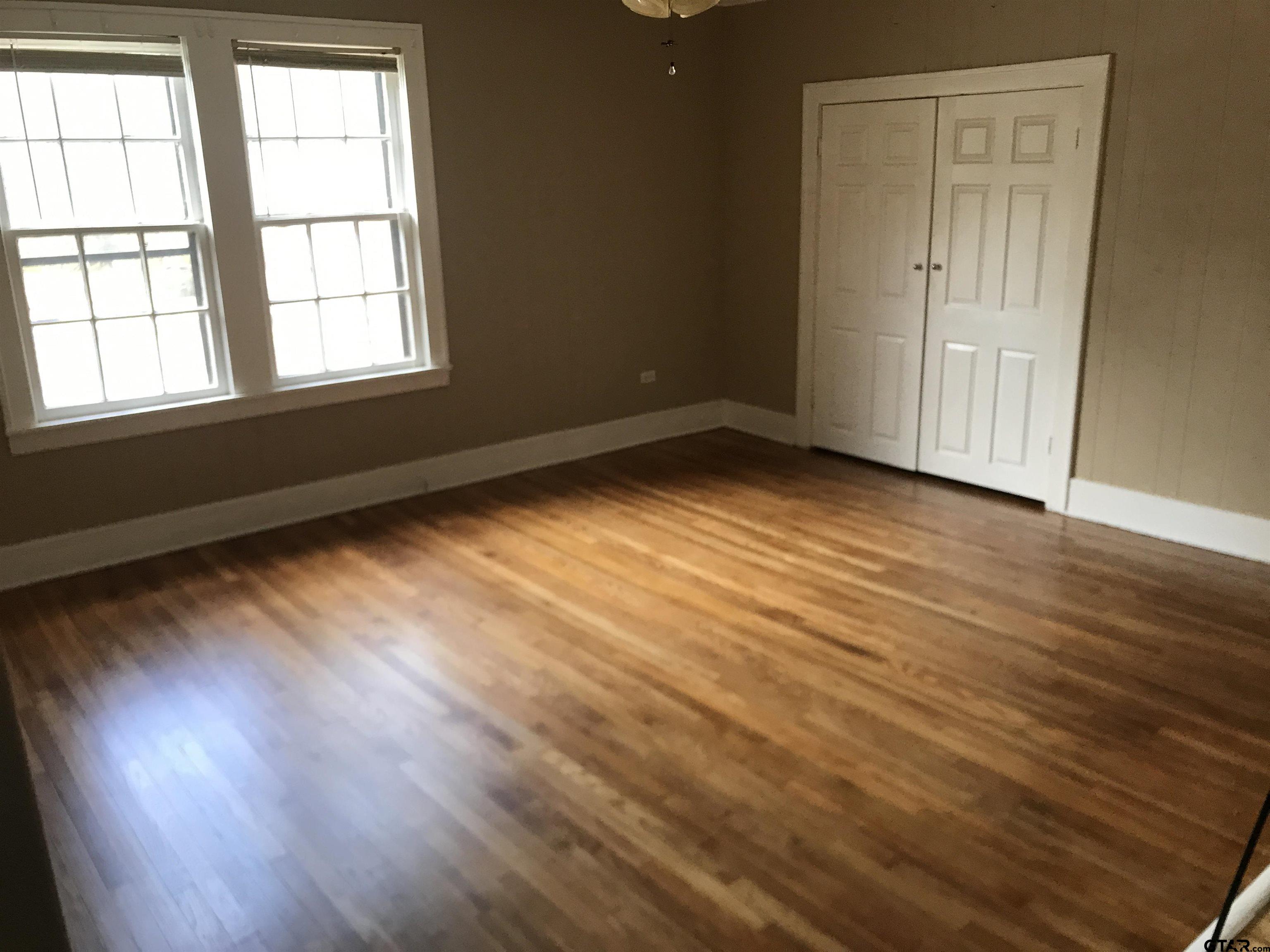 208 West Phillips Street, Unit 200 Tyler, TX 75701 - Photo 5 of 11 an empty room with wooden floor and windows