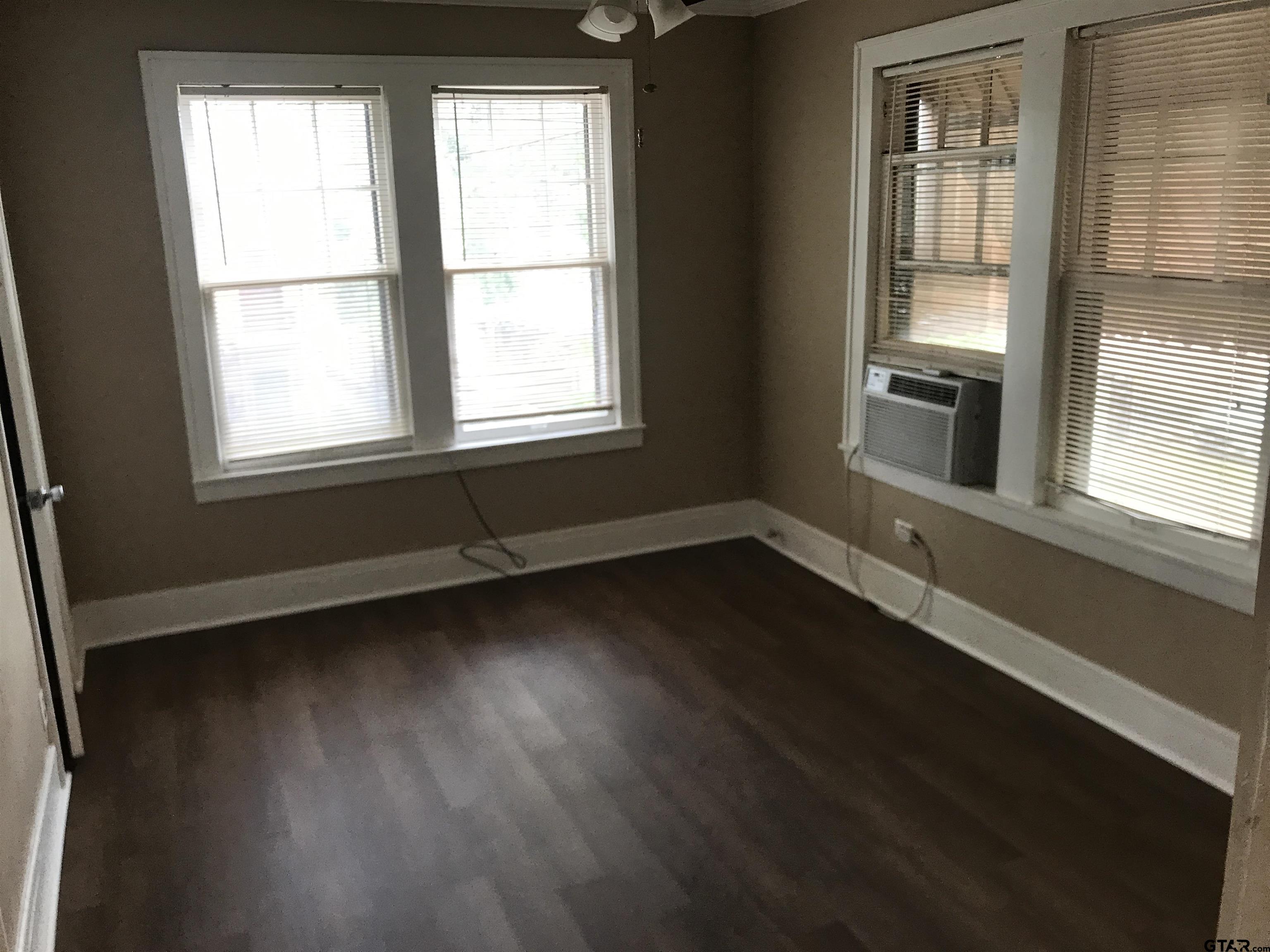 208 West Phillips Street, Unit 200 Tyler, TX 75701 - Photo 6 of 11 a view of an empty room with wooden floor and a window