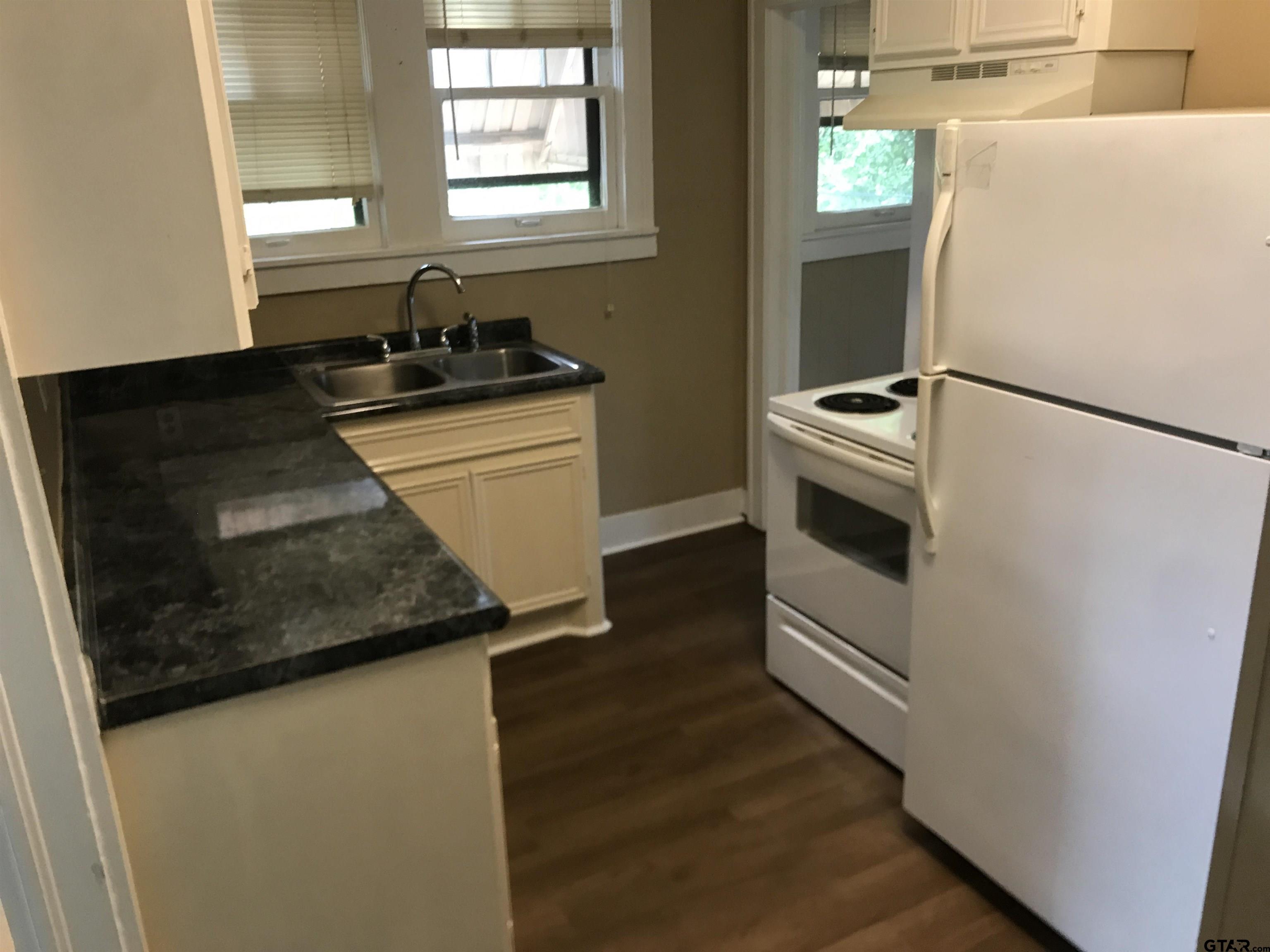 208 West Phillips Street, Unit 200 Tyler, TX 75701 - Photo 8 of 11 a kitchen with granite countertop a sink and a refrigerator