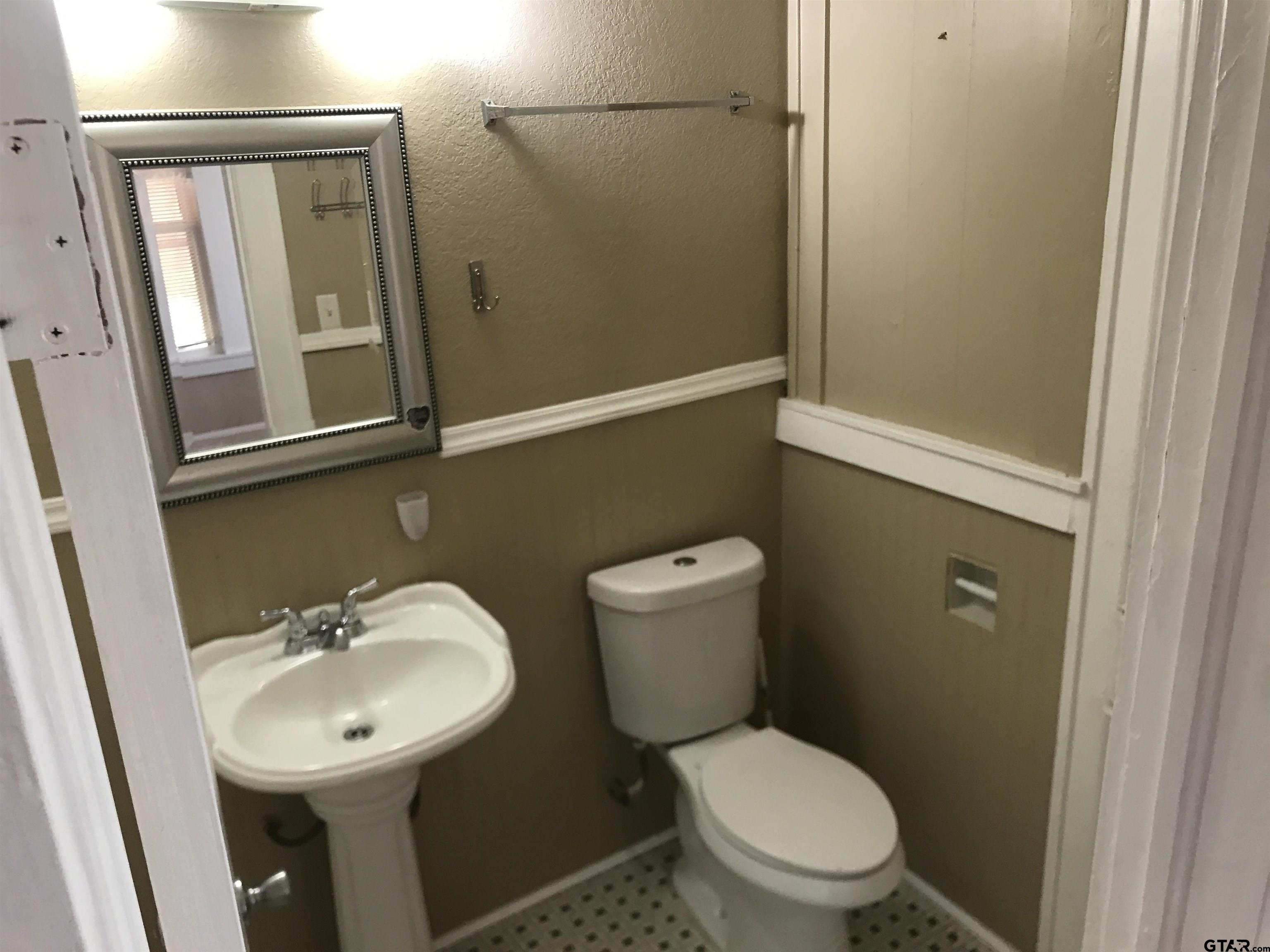 208 West Phillips Street, Unit 200 Tyler, TX 75701 - Photo 9 of 11 a bathroom with a toilet a sink and mirror