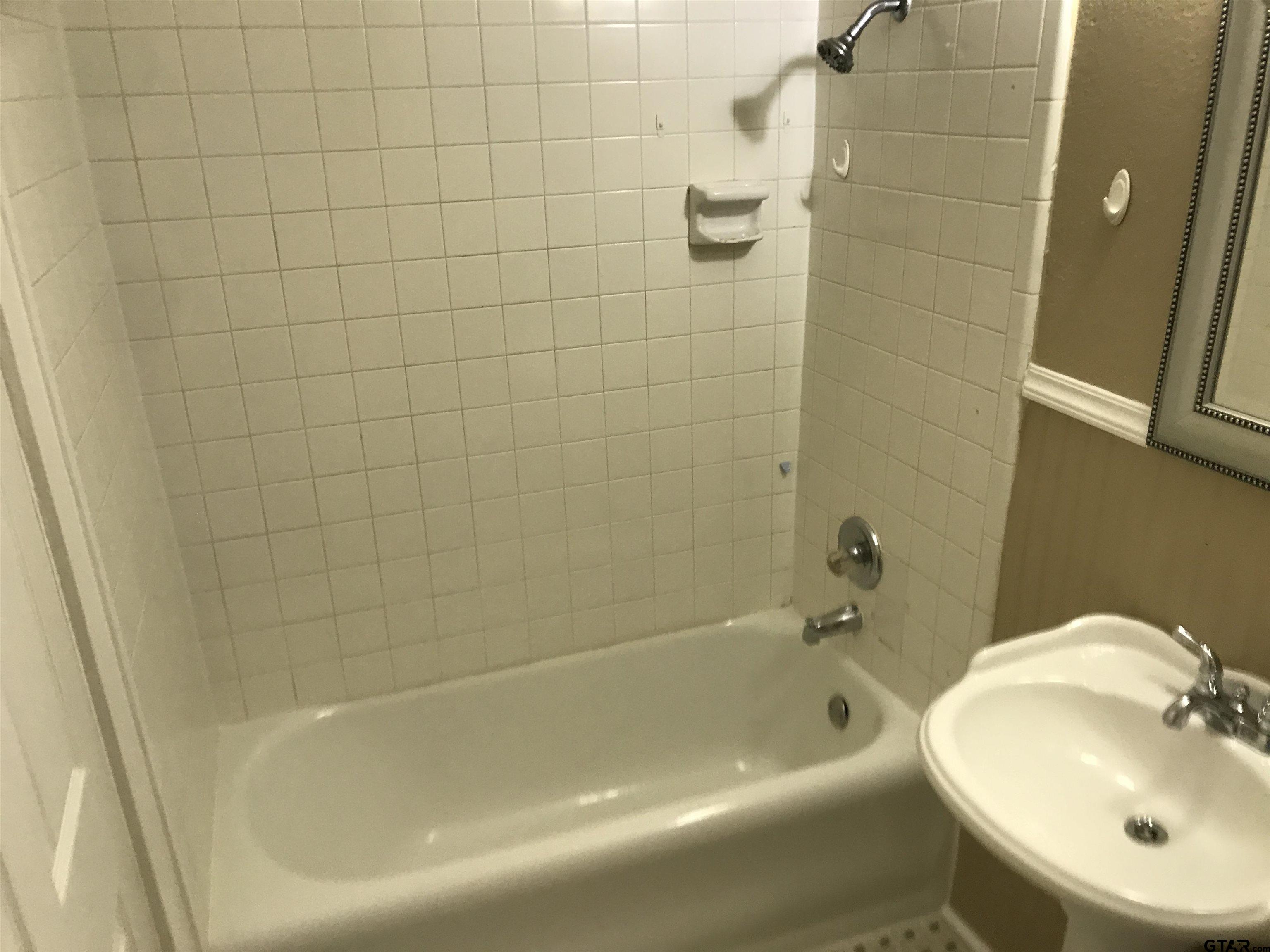 208 West Phillips Street, Unit 200 Tyler, TX 75701 - Photo 10 of 11 a bath tub sitting next to a white sink and a toilet