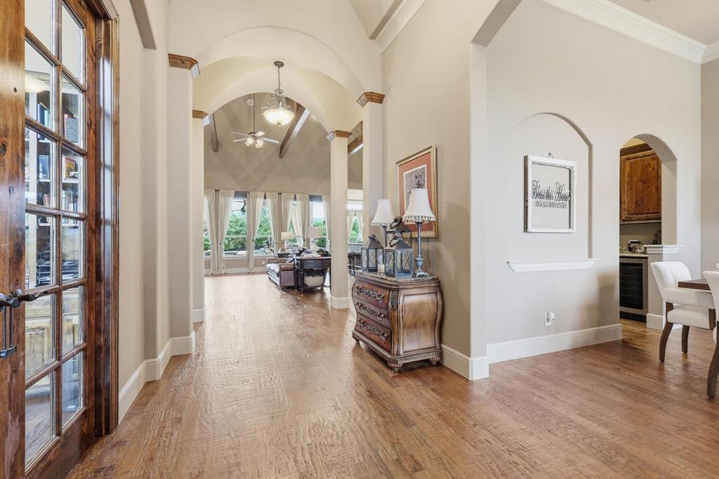 406 Spurgin Road Lucas, TX 75002 - Photo 2 of 39 Hallway with arched walkways, light wood-style flooring, beverage cooler, vaulted ceiling, and crown molding