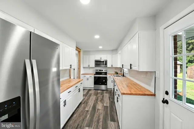 a large white kitchen with a refrigerator a stove a sink and a window