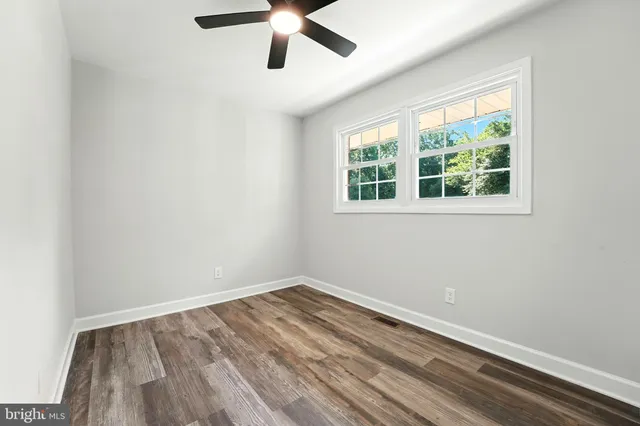 an empty room with a window and a ceiling fan