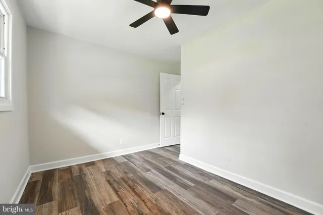 an empty room with wooden floor ceiling fan and windows