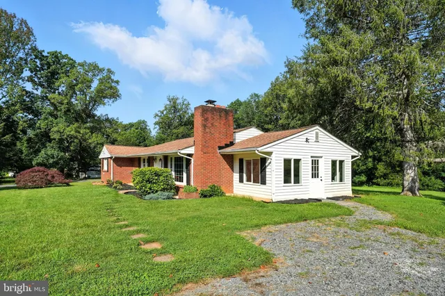 a front view of a house with a garden and trees