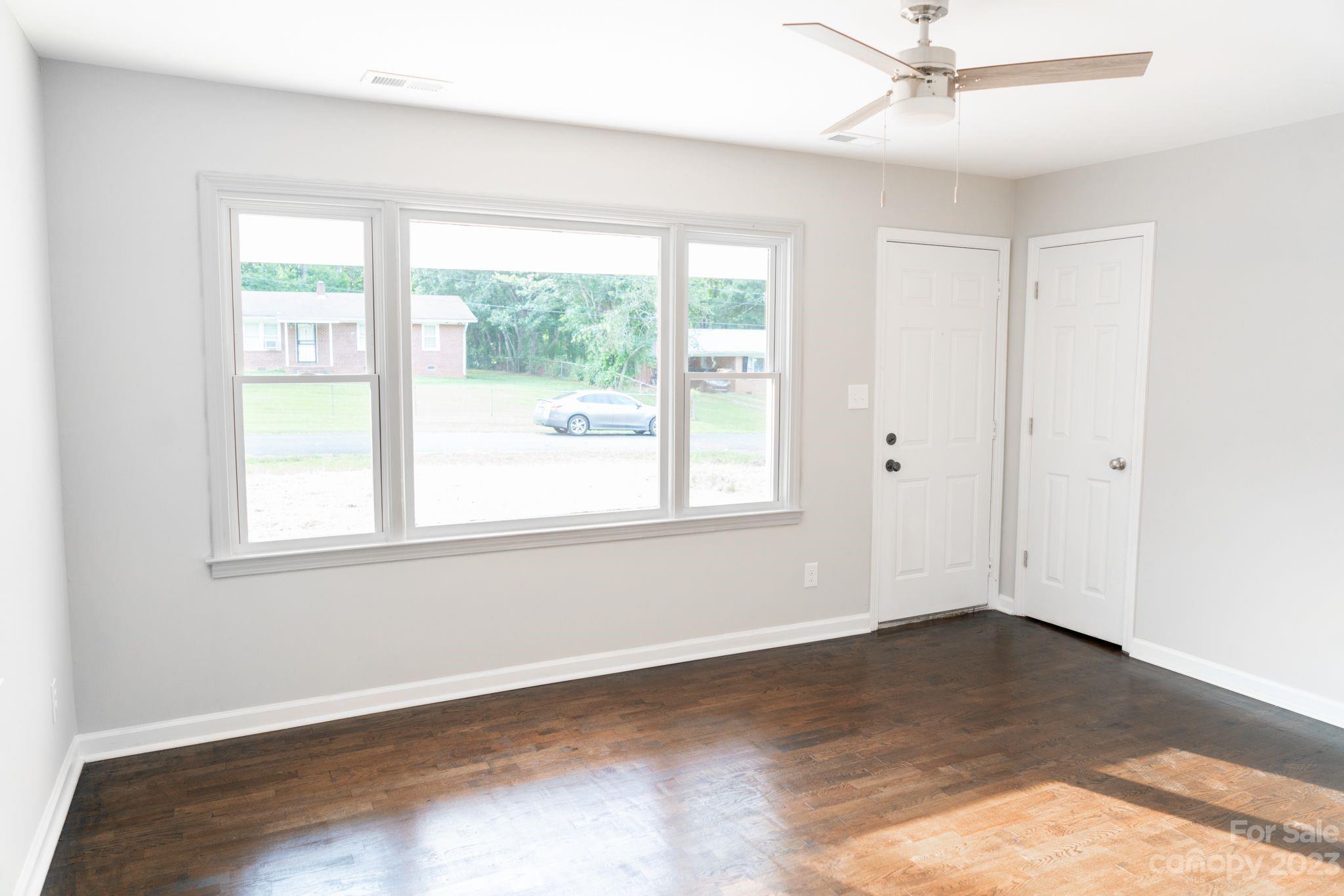41276 Kings Road New London, NC 28127 - Photo 2 of 12 an empty room with wooden floor fan and windows