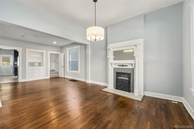a view of an empty room with wooden floor fireplace and a window