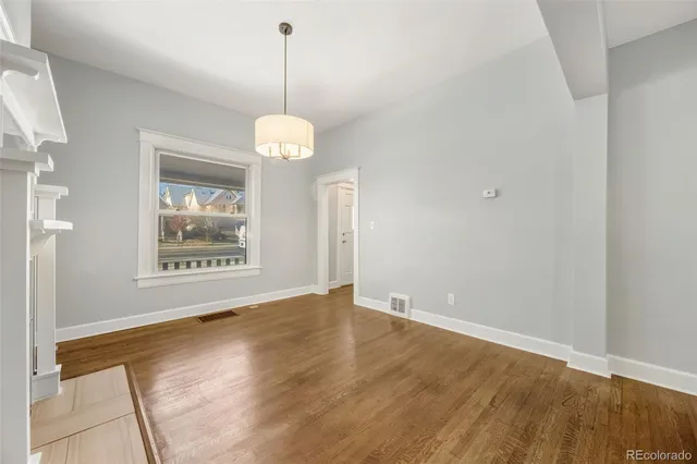 a view of an empty room with a window and wooden floor