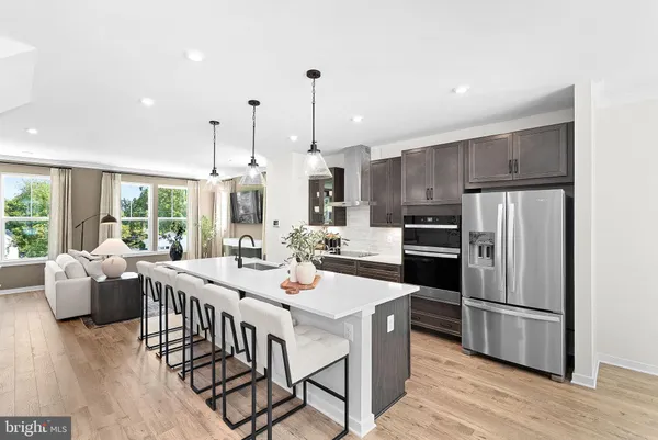 a kitchen with stainless steel appliances kitchen island granite countertop a kitchen island hardwood floor and a view of living room