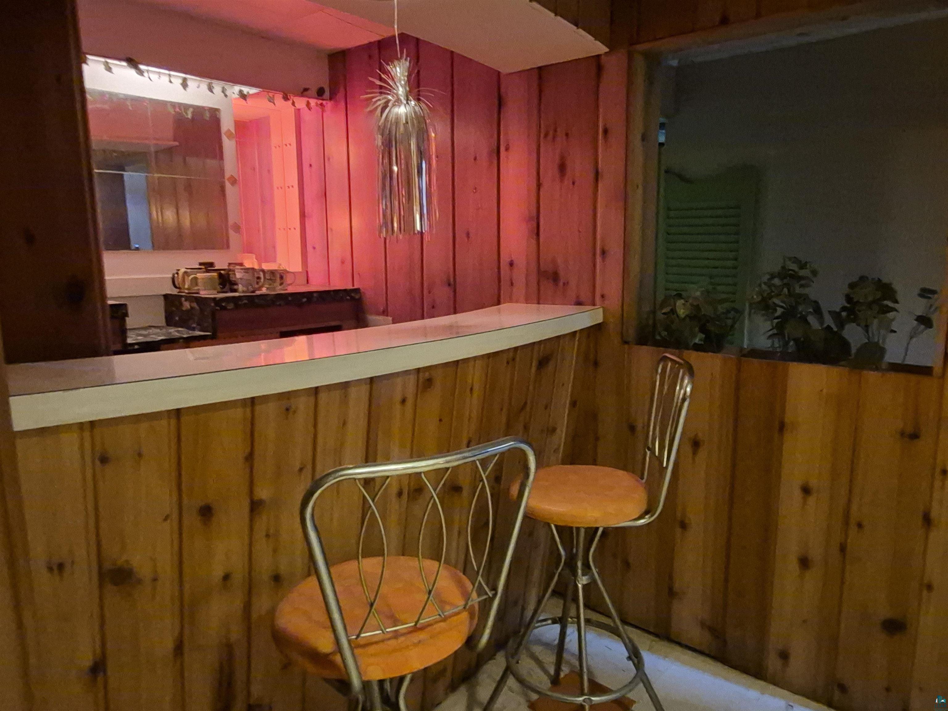 2109 West 22nd Street Duluth, MN 55811 - Photo 20 of 29 Built-in bar area featuring wood paneling, a white countertop, and a window opening to another space
