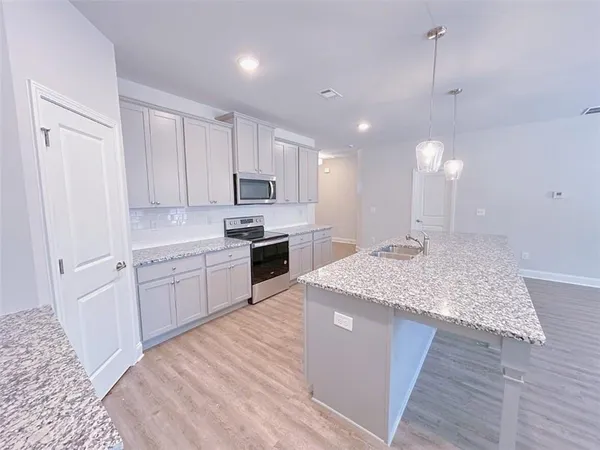 a kitchen with kitchen island sink stove and white cabinets