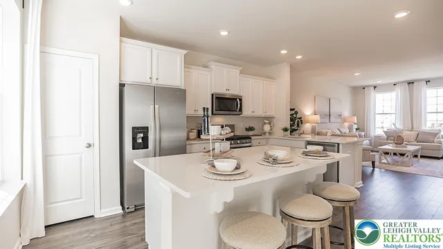 a kitchen with stainless steel appliances granite countertop a stove a refrigerator a sink a dining table and chairs with wooden floor