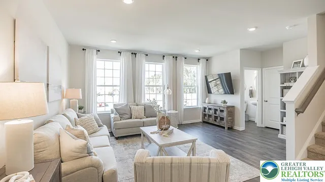 a living room with furniture flat screen tv and a large window