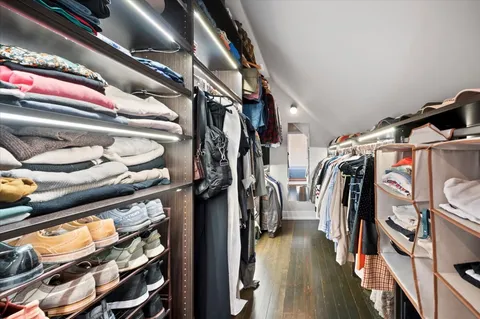 a view of walk in closet with clothes and shoes