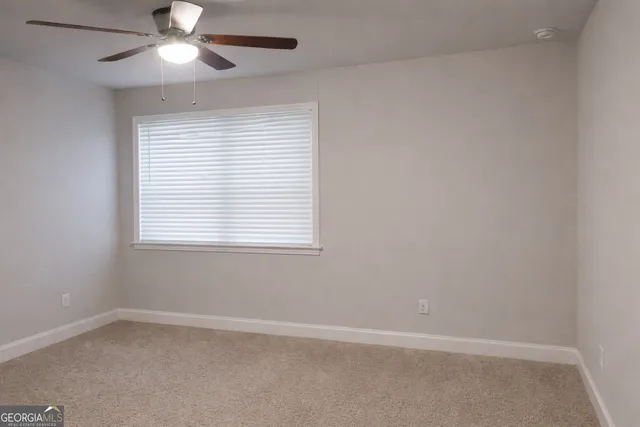 an empty room with a window and a fan