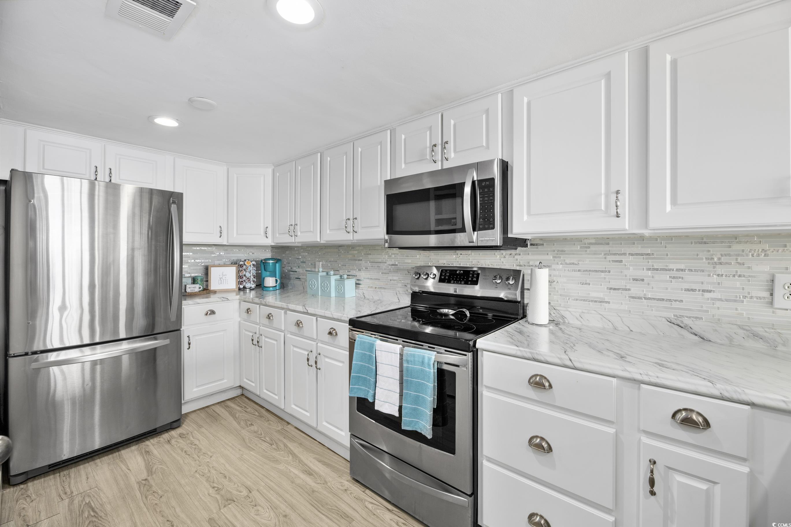 1108 North Waccamaw Drive, Unit 304 Murrells Inlet, SC 29576 - Photo 9 of 34 Kitchen featuring appliances with stainless steel finishes, white cabinets, recessed lighting, and light wood finished floors