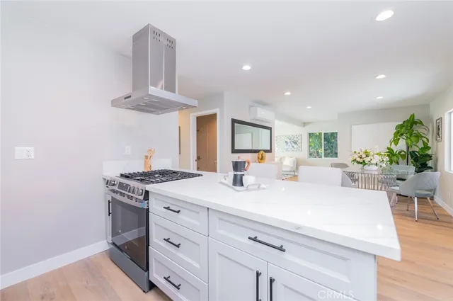 a kitchen with a stove a chandelier and a wooden floor