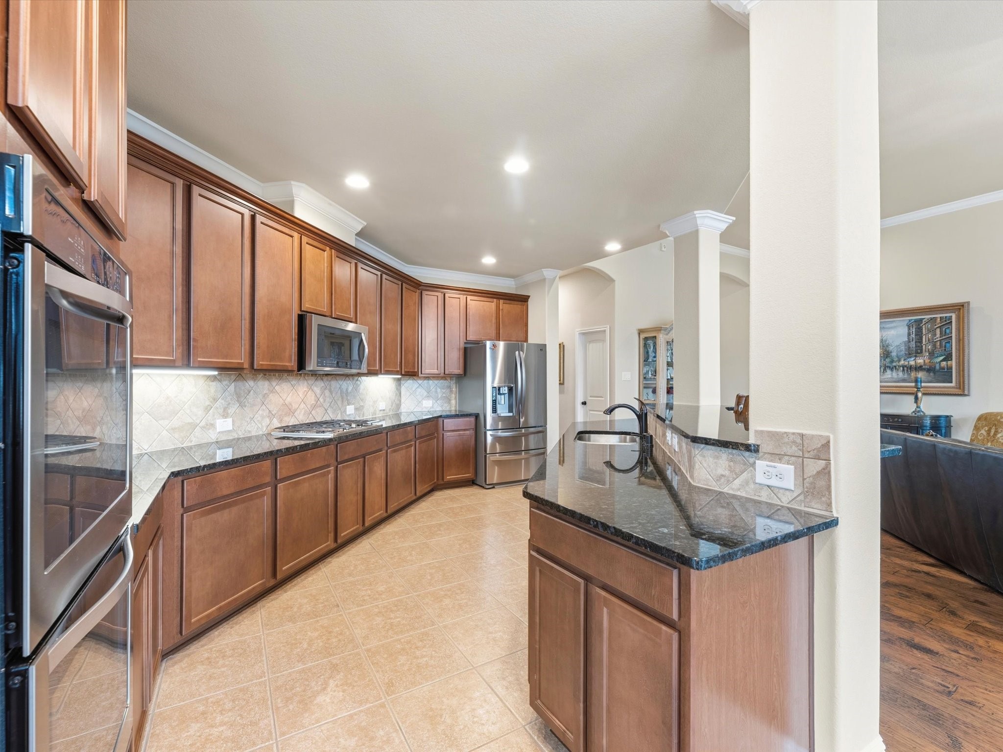 3907 Randle Ridge Court Fulshear, TX 77441 - Photo 11 of 46 Spacious kitchen with ample wooden cabinetry, granite countertops, and stainless steel appliances. Features a breakfast bar, recessed lighting, and a tiled floor for easy maintenance.