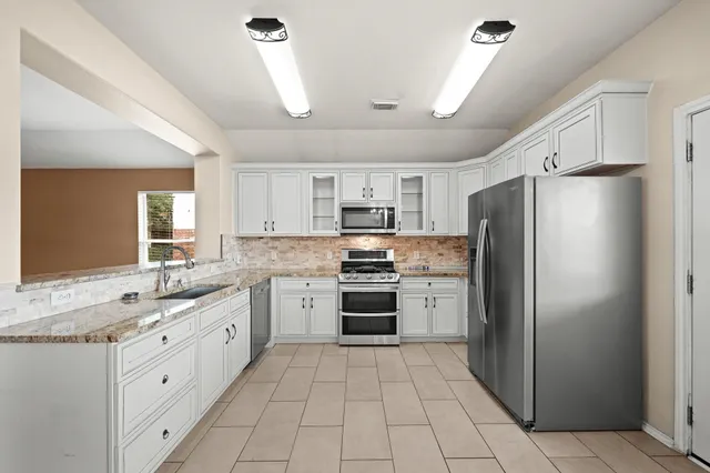 a kitchen with white cabinets appliances and a sink