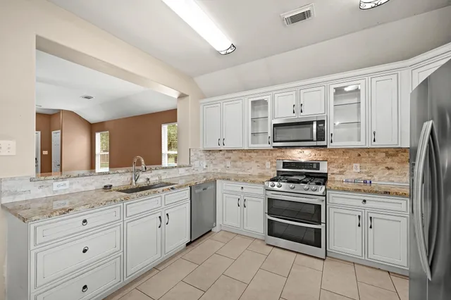 a kitchen with stainless steel appliances a refrigerator a sink cabinets and wooden floor