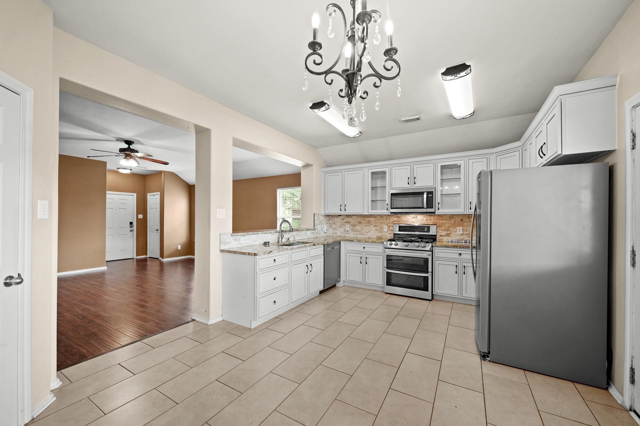 2813 Waterside Trail Pearland, TX 77584 - Photo 13 of 25 a kitchen with stainless steel appliances a refrigerator a sink cabinets and wooden floor