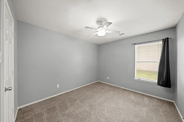 an empty room with closet and a chandelier fan