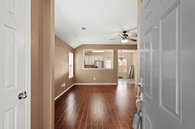 an empty room with wooden floor and windows