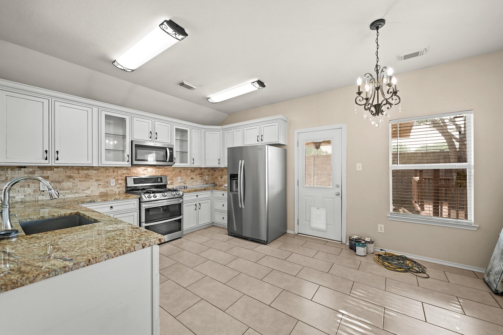 2813 Waterside Trail Pearland, TX 77584 - Photo 10 of 25 a kitchen with stainless steel appliances granite countertop a refrigerator and a stove top oven