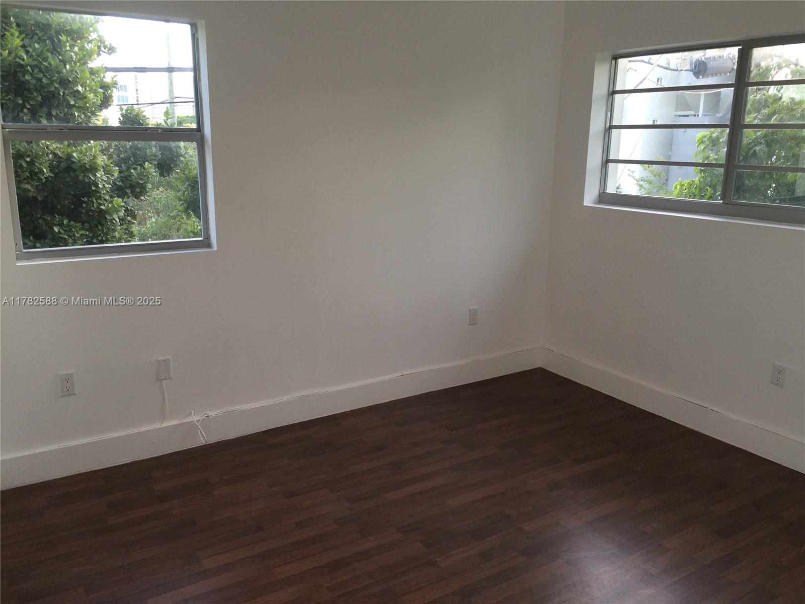 7025 Rue Granville, Unit 3 Miami Beach, FL 33141 - Photo 18 of 21 an empty room with wooden floor and windows