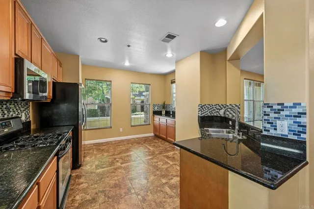 a kitchen with stainless steel appliances granite countertop a sink a stove and a refrigerator