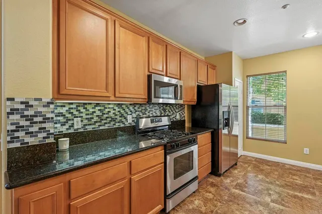 a kitchen with stainless steel appliances granite countertop a stove a sink and a microwave