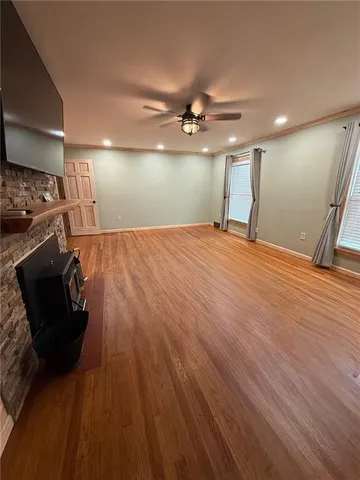 a view of an empty room with wooden floor fireplace and a window