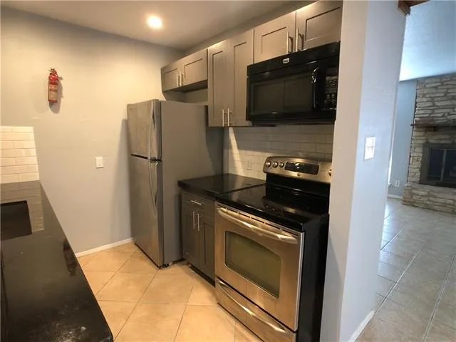 a kitchen with stainless steel appliances granite countertop a refrigerator stove and microwave