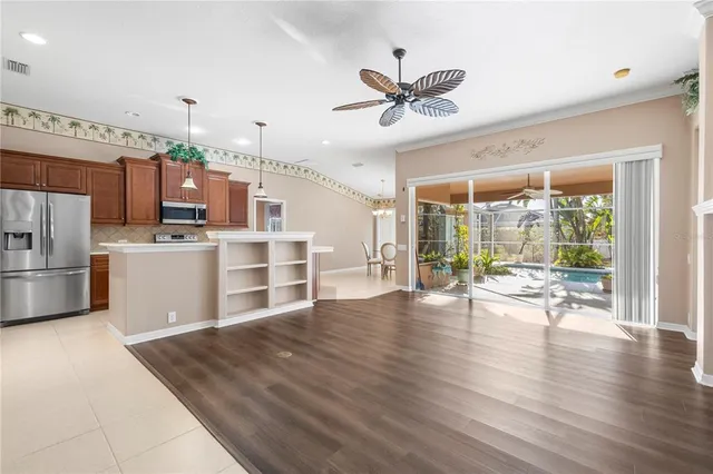 an empty room with wooden floor ceiling fan and windows