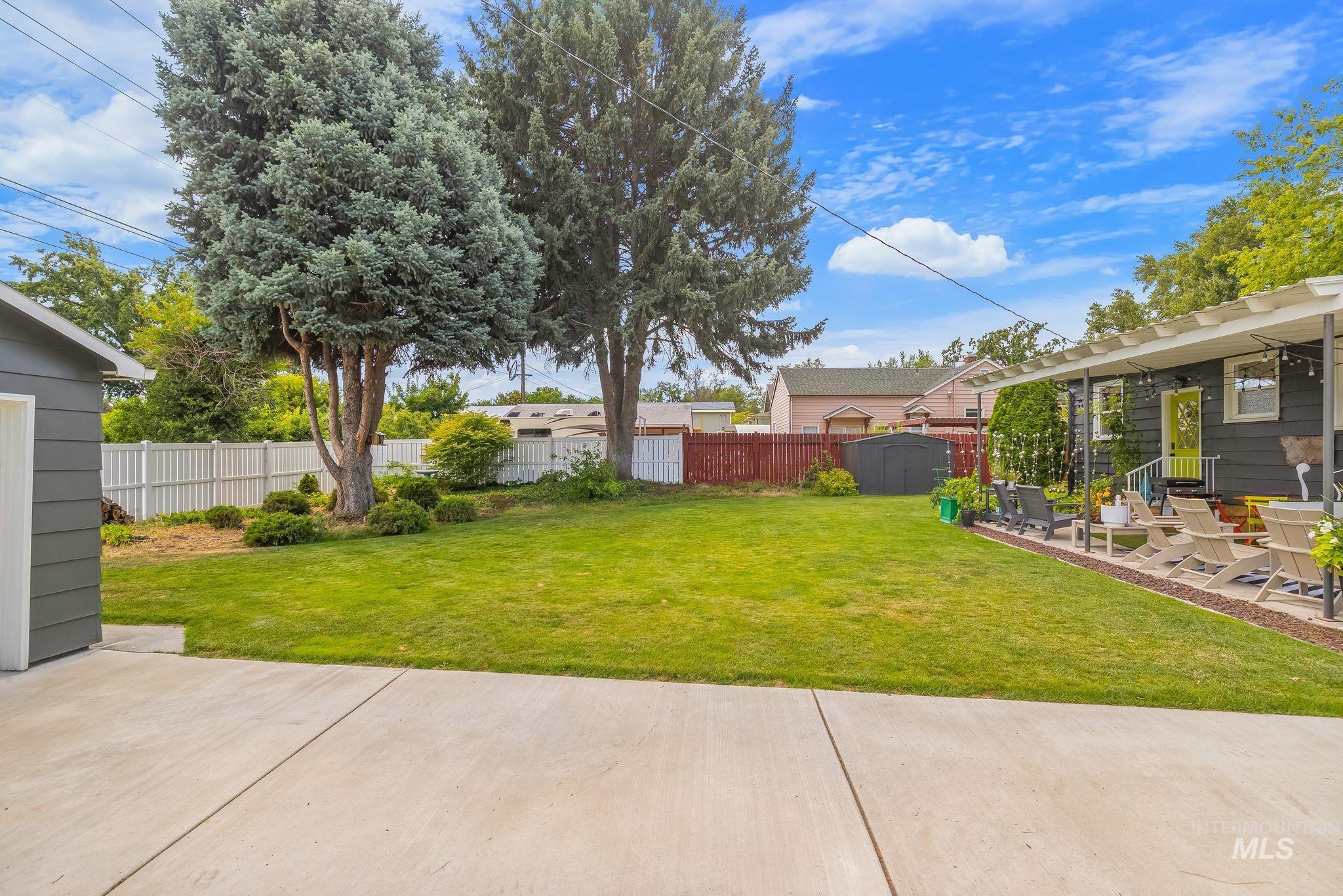 1315 8th Street Clarkston, WA 99403 - Photo 35 of 37 Expansive backyard featuring a large concrete patio, a pergola-covered outdoor seating area, a manicured lawn, and mature trees