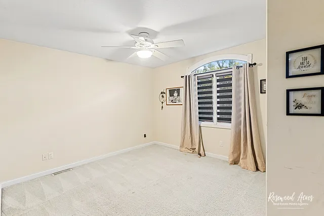 an empty room with windows and fan