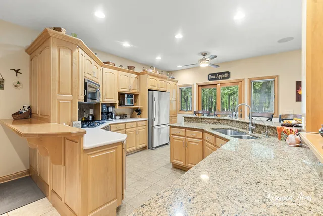 a large white kitchen with kitchen island a sink a stove a refrigerator cabinets and living room view