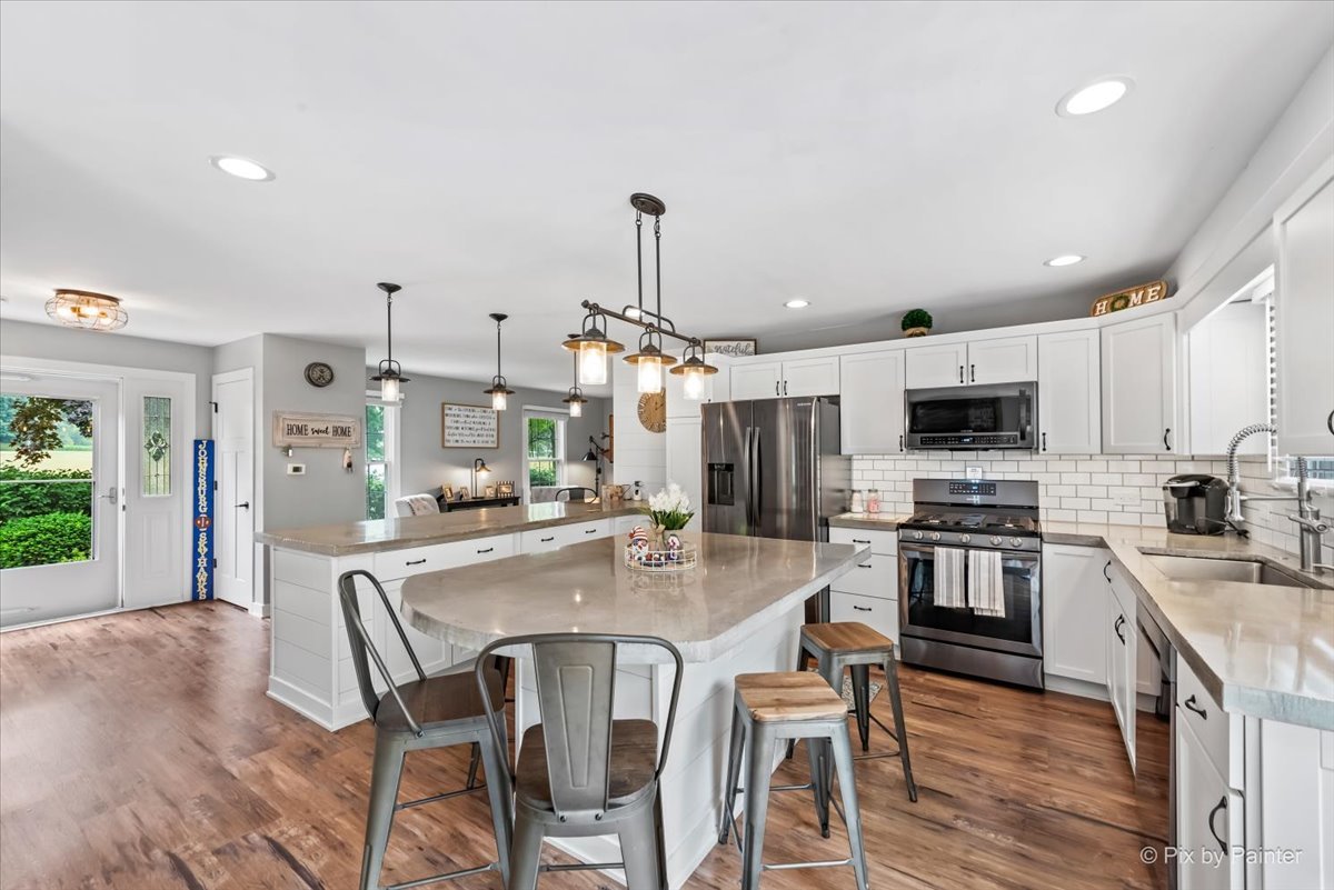3205 Ramsgate Lane Johnsburg, IL 60051 - Photo 5 of 41 a kitchen with stainless steel appliances kitchen island granite countertop a stove top oven a sink dishwasher a dining table and chairs with wooden floor