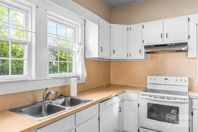 a kitchen with cabinets a sink and a stove next to a window