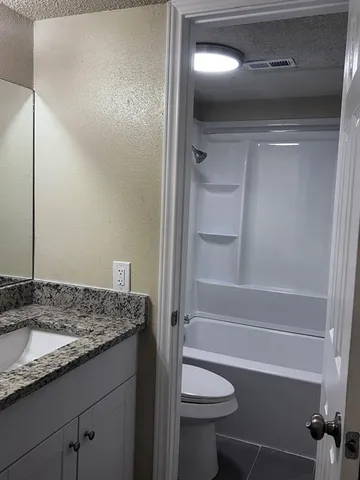 a bathroom with a granite countertop sink and toilet