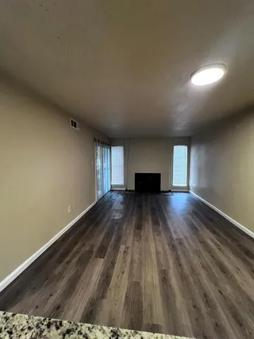a view of empty room with wooden floor and fireplace