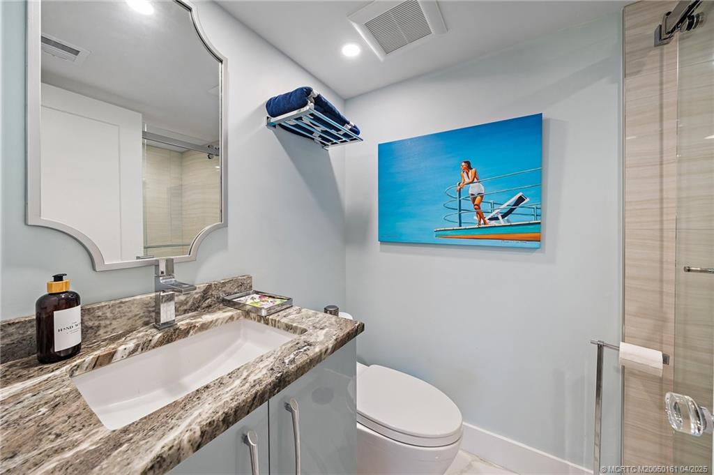 669 Northeast Plantation Road, Unit 201 Stuart, FL 34996 - Photo 32 of 37 a bathroom with a granite countertop sink a toilet and a mirror