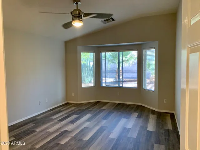 a view of empty room with wooden floor and fan