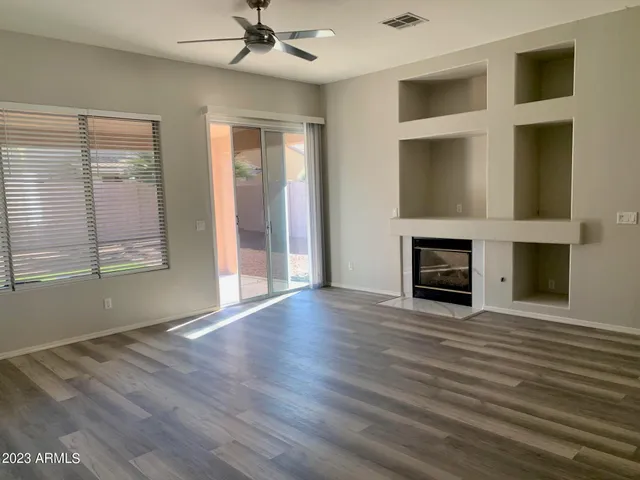 a view of an empty room with wooden floor fireplace and a window