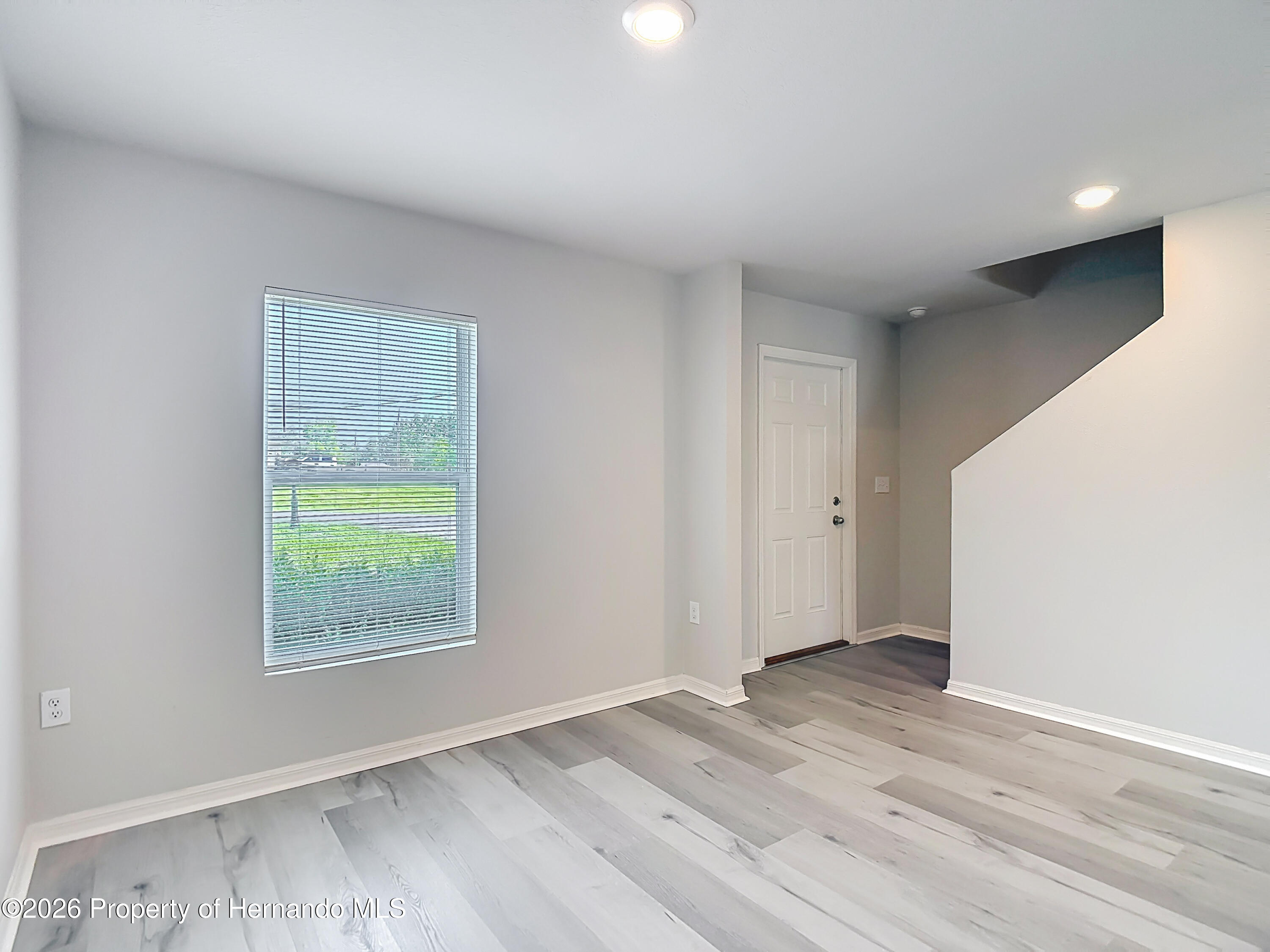 11374 Marcella Avenue Weeki Wachee, FL 34614 - Photo 12 of 70 an empty room with wooden floor and windows