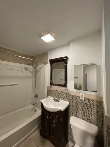 a bathroom with a sink a toilet a mirror and bathtub