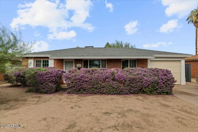 a front view of house with garden and trees